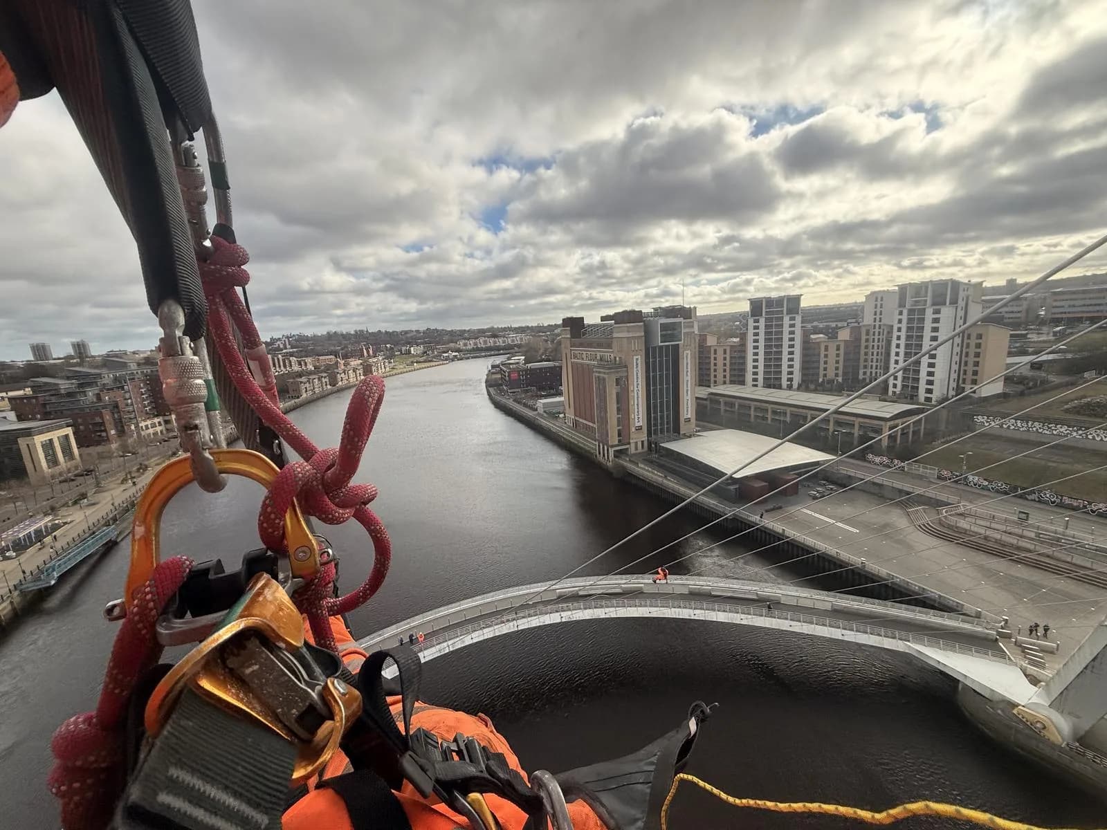 View from the top of a bridge tower with climbing rigging in shot, looking down the river