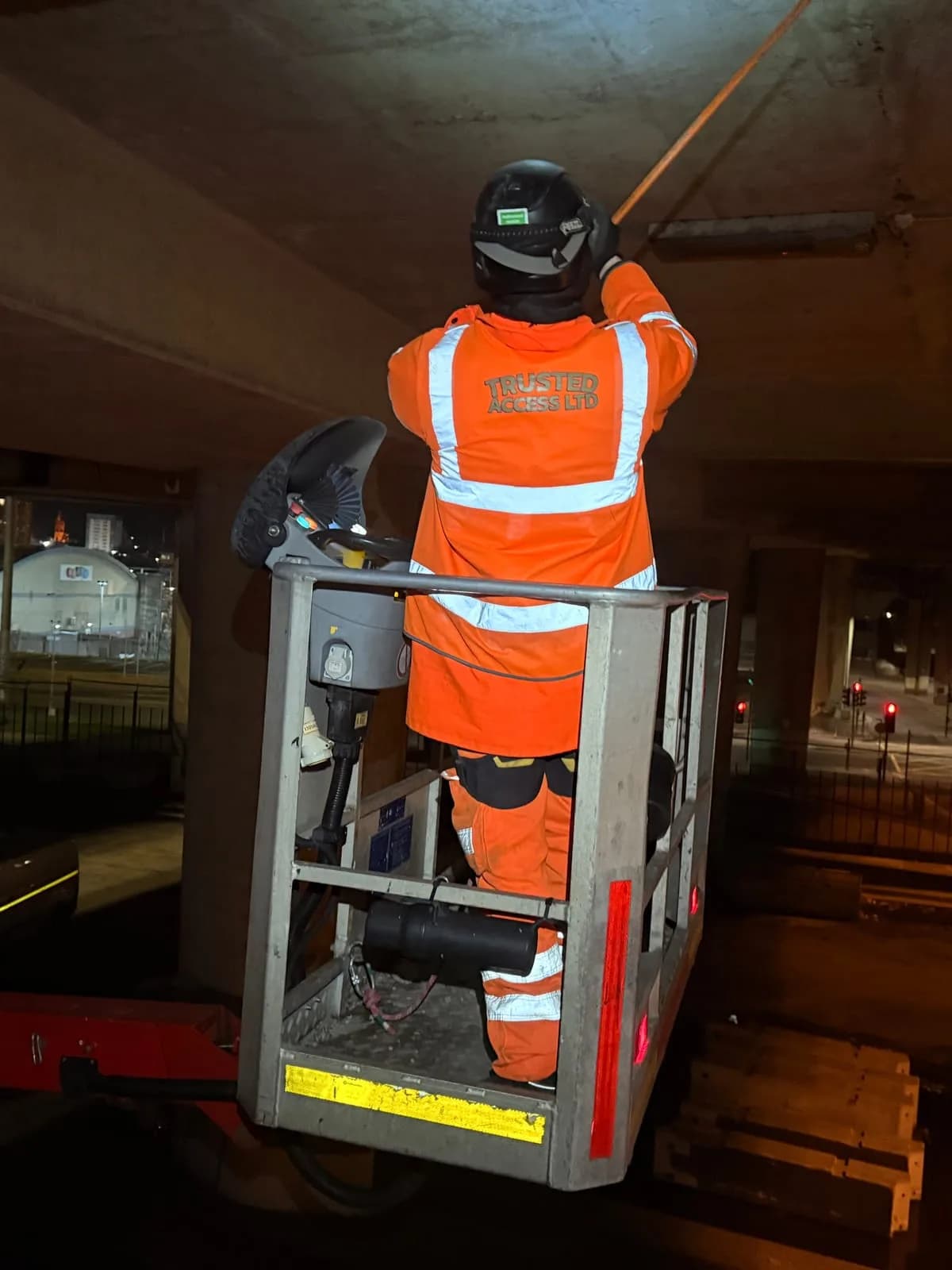 Trusted Access technician working on a flyover soffit from an elevated platform at night
